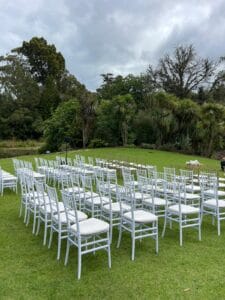 White and Gold Tiffany chairs arranged for an outdoor garden wedding ceremony, surrounded by greenery